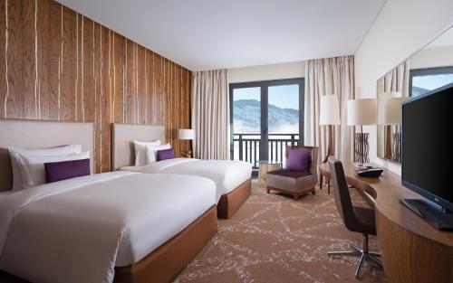 a hotel room with two beds and a desk and a television at Park Chalet, Shahdag, Autograph Collection in Shahdag