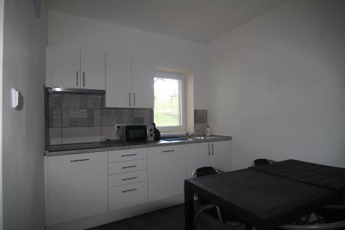 a kitchen with white cabinets and a table and a window at Trdlovy Apartmány a Chata Tatranec v areálu Jaškovské krčmy in Horní Těrlicko