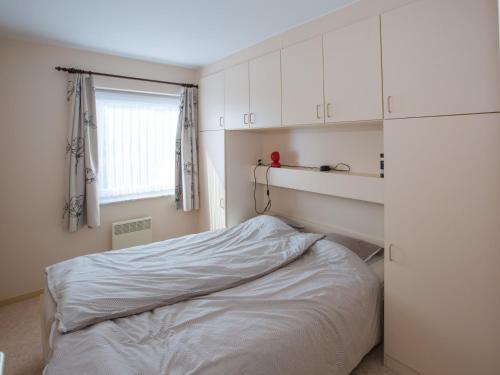 Schlafzimmer mit einem Bett mit weißen Schränken und einem Fenster in der Unterkunft Golf Azur Frejus with swimming pool in Middelkerke