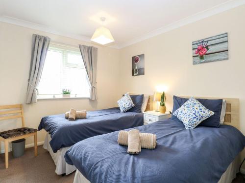 a bedroom with two blue beds and a window at Beach Croft in Lowestoft