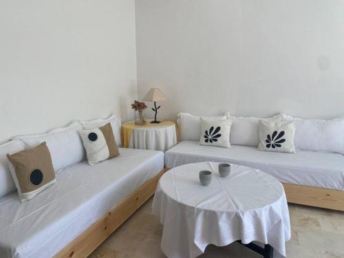 a living room with two white couches and a table at Logement entier et indépendant D in Rabat