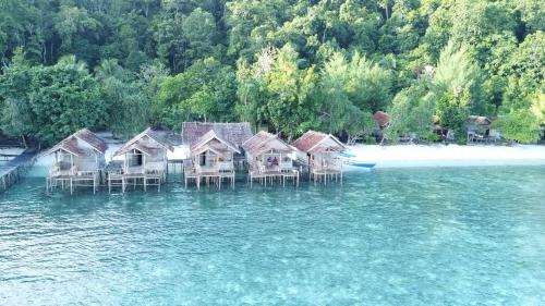 a group of houses sitting in the water at Firdas Bungalows in Waisai