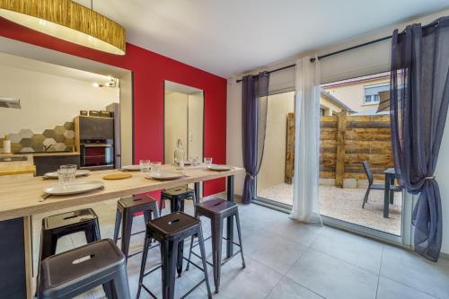 uma cozinha com paredes vermelhas e bancos de bar em Maison calme avec terrasse garage centre-ville B em Dijon