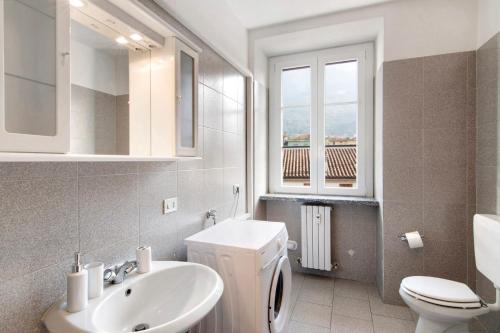 een badkamer met een wastafel en een toilet en een raam bij Greta House in Colico