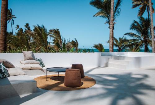 a patio with a couch and a table and palm trees at Ycona Eco-Luxury Resort, Zanzibar in Dikoni