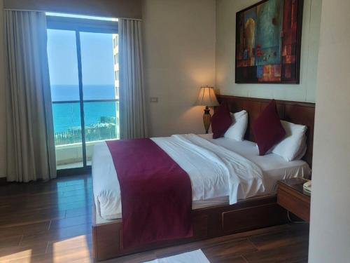 een slaapkamer met een bed en uitzicht op de oceaan bij King Suites Hotel in Beiroet