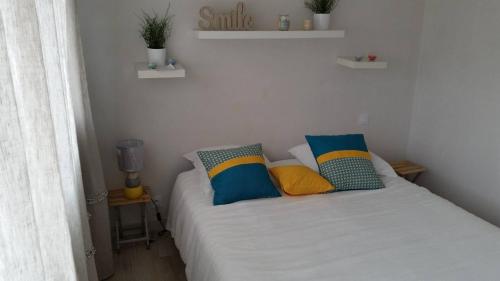 een kleine slaapkamer met een wit bed met kussens bij Maison récente à 300 m de la mer in Carantec