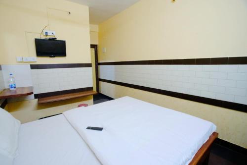 a room with two beds and a tv on the wall at Bava Inn in Chennai