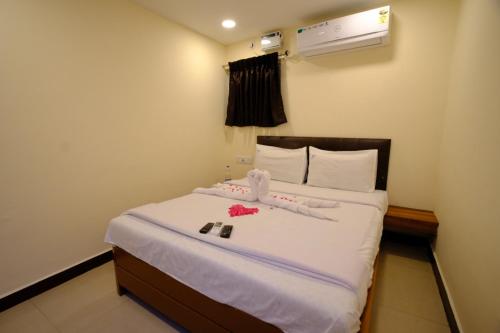 a bedroom with a bed with white sheets and flowers on it at Bava Inn in Chennai
