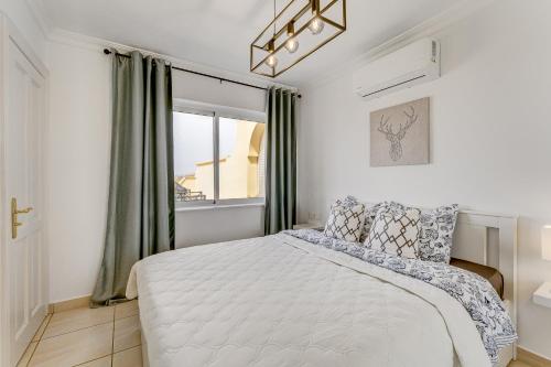 a white bedroom with a bed and a window at Ramada Costa Adeje Apartment in Adeje