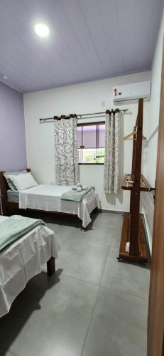 a bedroom with two beds and a window at Casa Ypê - Vila de São Jorge in Alto Paraíso de Goiás