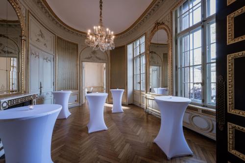 Habitación con mesas blancas y ventanas grandes. en Schlosshotel Berlin by Patrick Hellmann, en Berlín