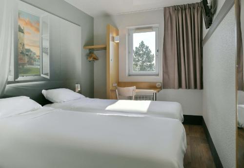 two beds in a hotel room with two windows at B&B HOTEL Le Mans Nord 1 in Saint-Saturnin