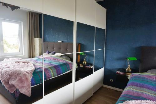 um quarto com uma cama e uma parede azul em Ruime en centrale woning zuidrand Antwerpen em Aartselaar