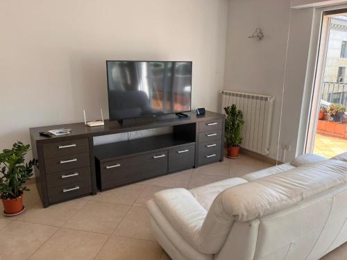 uma sala de estar com televisão e um sofá branco em Diamond Rooftop by Babylon Stay em Nápoles