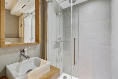 une salle de bain blanche avec un lavabo et une douche dans l'établissement Élégance confort à l’Odéon by Weekome, à Paris