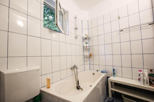 uma casa de banho em azulejos brancos com uma banheira e uma janela em Casa Dell'Edera em Bucareste