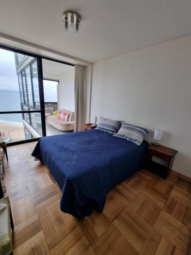 a bedroom with a blue bed and a large window at Vista al Mar Departamento - Edificio Acapulco in Viña del Mar
