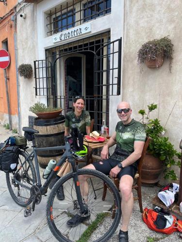 a man and a woman sitting at a table with a bike at Locanda Il Sigillo B&B e Ristorante in Rosignano Marittimo