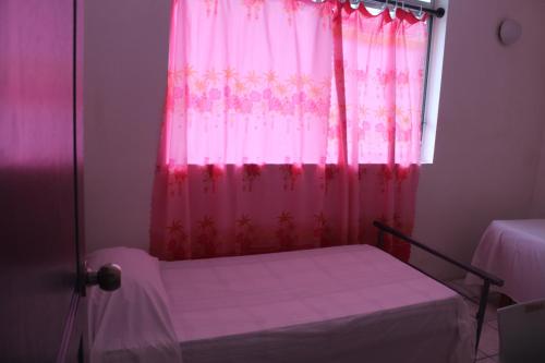 a bedroom with a pink curtain and a window at HIME LODGE in Papeete