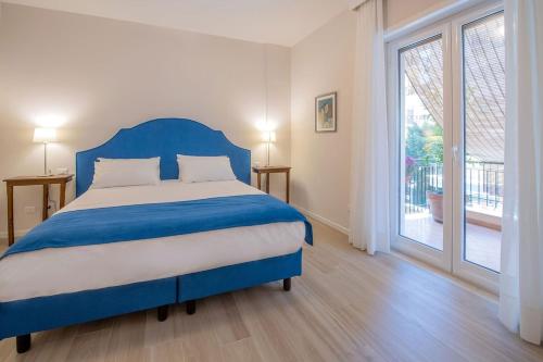 een slaapkamer met een blauw bed en een glazen schuifdeur bij Gemma di Zagara Apartment in Sorrento