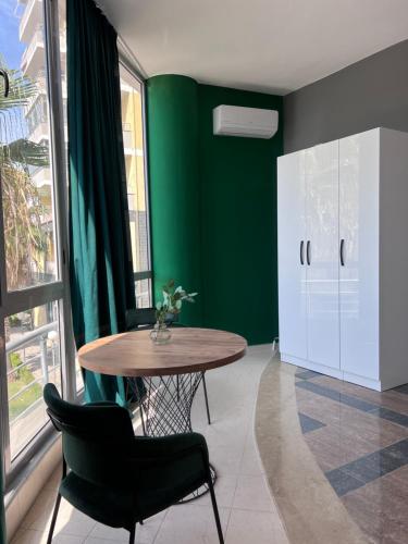 a dining room with a table and a green wall at Cactus Apartments in Durrës