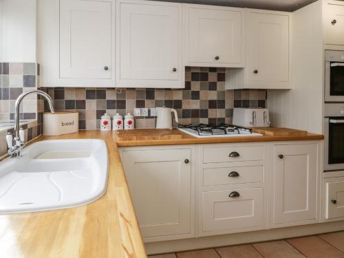 a kitchen with white cabinets and a sink at 1 Tan Yr Ywen in Conwy