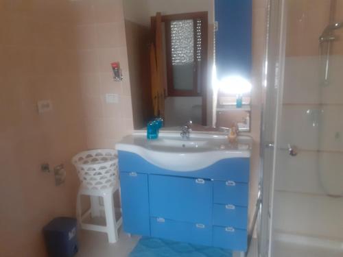 y baño con lavabo azul y espejo. en I Paoletti apartment! en Quartu SantʼElena
