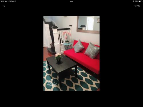 a red couch in a living room with a table at Gateway en-suite bedroom next jhu in Baltimore
