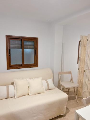 a white living room with a couch and a chair at El rincon de Marisa in Vejer de la Frontera