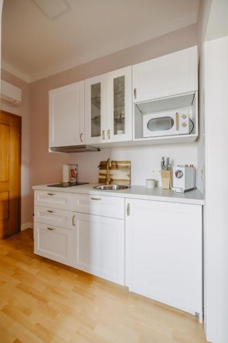 a white kitchen with white cabinets and a microwave at Villa SEEhnsucht in Jois