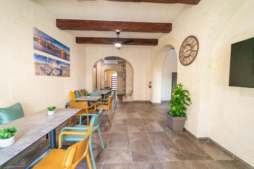 ein Restaurant mit Tischen und Stühlen und einer Uhr an der Wand in der Unterkunft 49 Sunrise Lodge in Għajnsielem