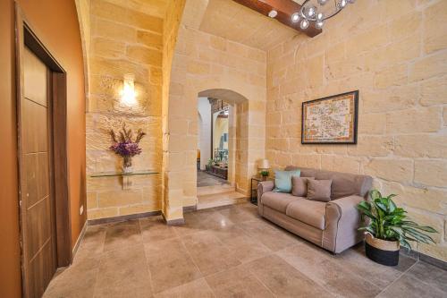 a living room with a couch and a stone wall at 49 Sunrise Lodge in Għajnsielem