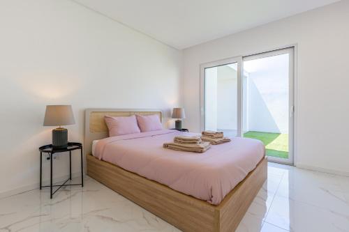 a white bedroom with a large bed with a window at Villa Tapisco in Lourinhã