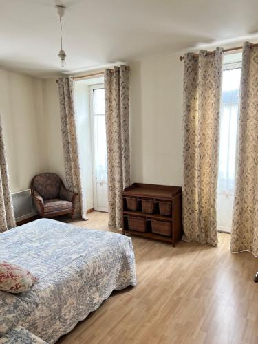 a bedroom with a bed and a chair and windows at Appartement Bord des quais 1er étage centre ville in Quimper