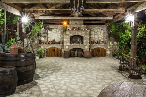 a large room with a stone building with wooden doors at Guest House Kusika in Sighnaghi