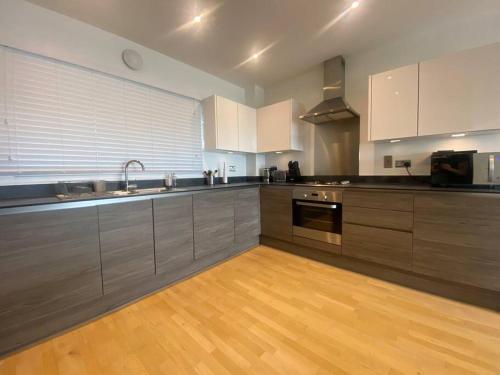 een grote keuken met houten vloeren en roestvrijstalen apparatuur bij Stunning 2 Bedroom Apartment in Croydon