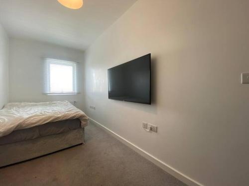 een slaapkamer met een bed en een flatscreen-tv aan de muur bij Stunning 2 Bedroom Apartment in Croydon