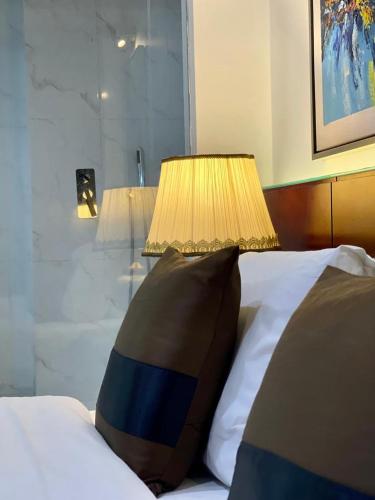 a bed with a pillow and a lamp on it at Empyrean Dhaka City Centre in Dhaka