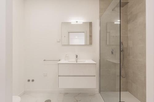 a white bathroom with a sink and a shower at Villa Tapisco in Lourinhã