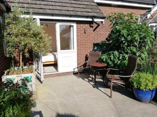 a patio with a white door and some plants at Gables Farm, Self contained flat by Middlewood Way in Poynton