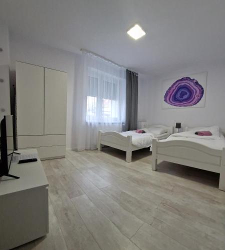 a white room with two beds and a tv at Apartament Agat in Lwówek Śląski