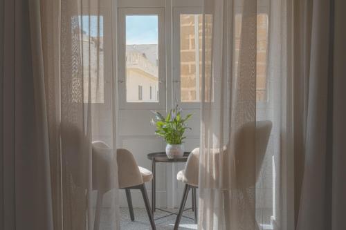 a room with a window with a table and chairs at Maria Rosa Suites in Victoria