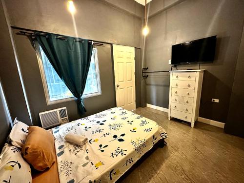 um quarto com uma cama, uma cómoda e uma televisão em Limewood Residences- Bago City near Bacolod em Bago