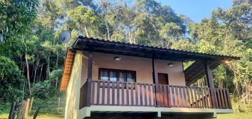 ein kleines Haus mit Balkon in einem Wald in der Unterkunft Chalé Céu de Minas in Visconde De Maua