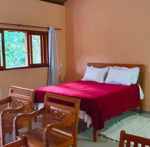 - une chambre avec un lit doté d'un couvre-lit rouge dans l'établissement Chalé Céu de Minas, à Visconde de Mauá
