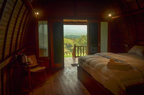 a bedroom with a bed and a large window at The Hills Kerinci in Kayu Aro