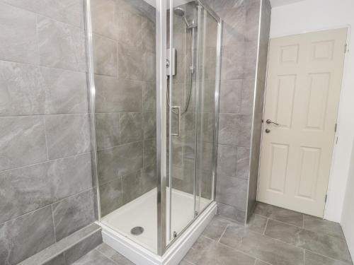 a shower with a glass door in a bathroom at Cae Teg in Llanfairpwllgwyngyll