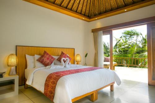 a bedroom with a large bed and a balcony at Pesantian Villa and Warung in Ubud