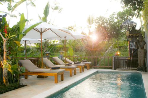 een zwembad met stoelen en parasols naast een resort bij Pesantian Villa and Warung in Ubud